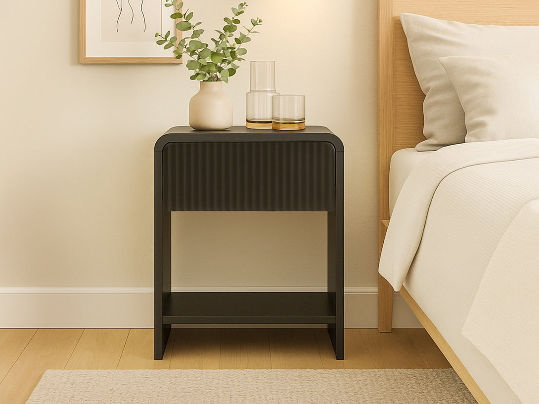 Black Cannock Bedside Table with fluted-panel drawer, open shelf, and matte finish, styled in a contemporary bedroom setting.